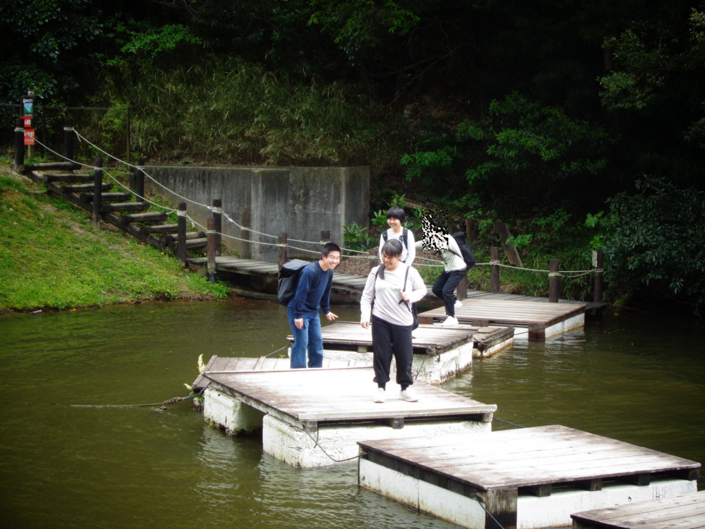 池の上に浮かんでいるいかだの上を順番に渡るアスレチックを楽しんでいます。