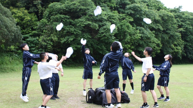 青春の1ページを撮ろうをテーマにクラスで話し合って、クラス8人が丸くなって帽子を上に投げている